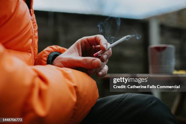 close-up of a mans hand holding a slim straight cigarette - paquete de cigarrillos fotografías e imágenes de stock
