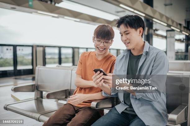 2 generation z asian chinese teenage boy looking at smartphone in subway train - asian generation z stock pictures, royalty-free photos & images