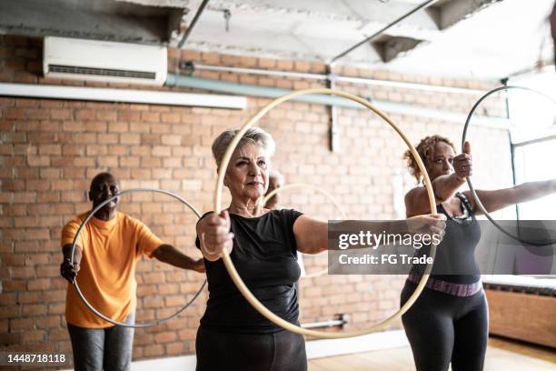 seniorinnen in einer übungsklasse - gymnastikreifen stock-fotos und bilder