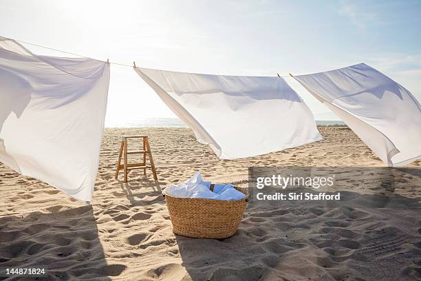 white sheets hanging on laundry line at beach - sheet bedding stock-fotos und bilder
