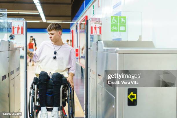 portrait of caucasian student in wheelchair on subway turnstile to access public transportation. - fauteuil handicap stock pictures, royalty-free photos & images