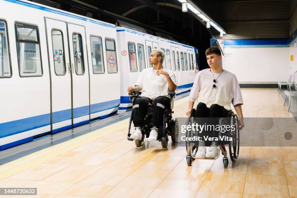 portrait of latin american students men on wheelchair waiting on subway platform with backpacks. - fauteuil handicap stock pictures, royalty-free photos & images