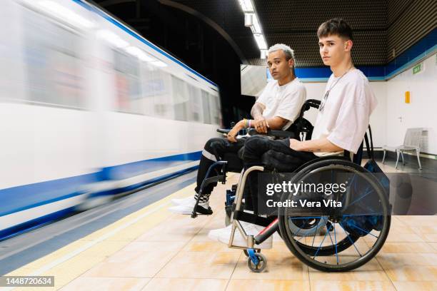 portrait of latin american students men on wheelchair waiting on subway platform with backpacks. - fauteuil handicap stock pictures, royalty-free photos & images