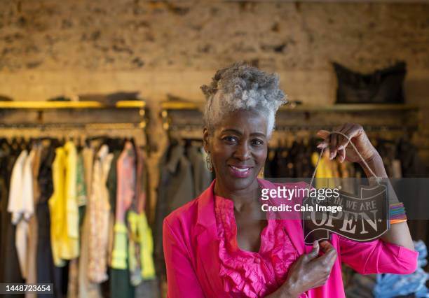 portrait confident senior female shop owner holding open sign - セブンオークス ストックフォトと画像