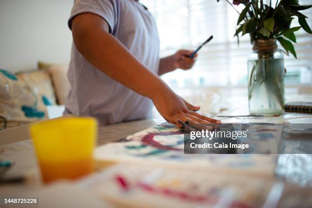 boy finger painting at table - vingerverf stockfoto's en -beelden