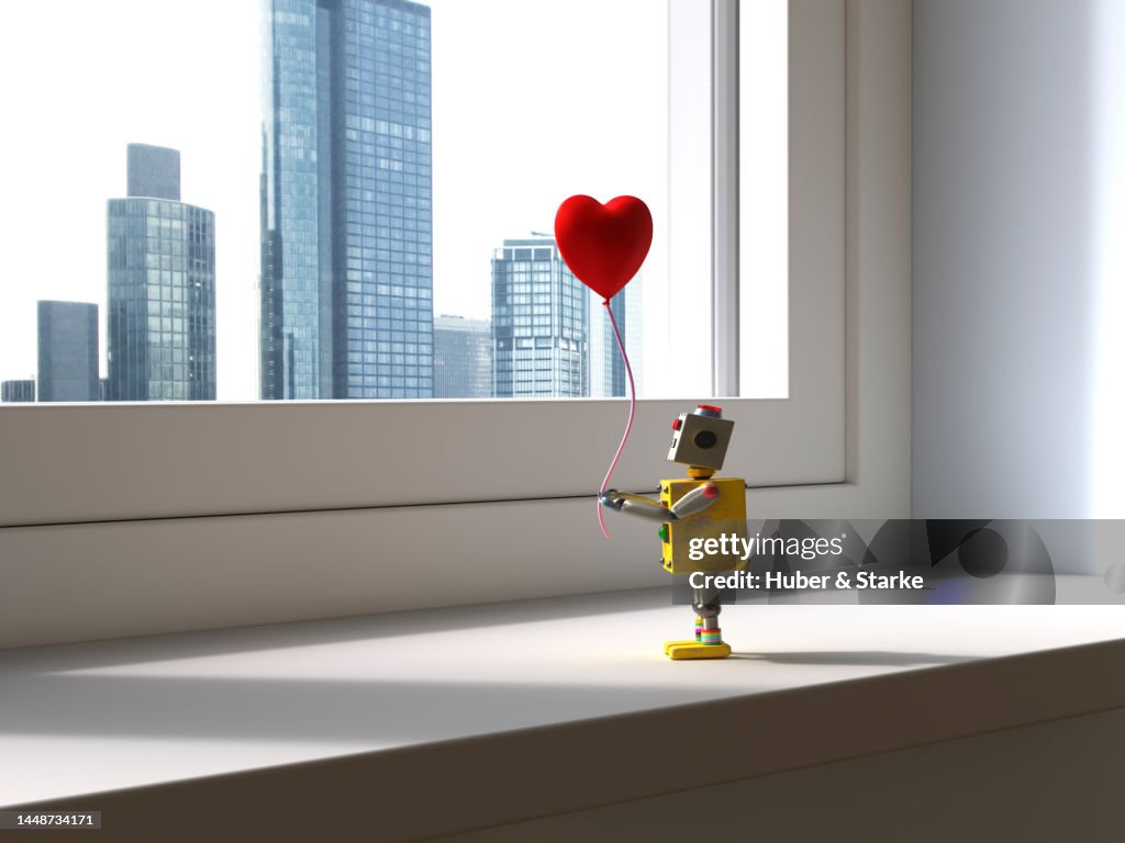 Little robot with heart shaped balloon in hand looks out of window