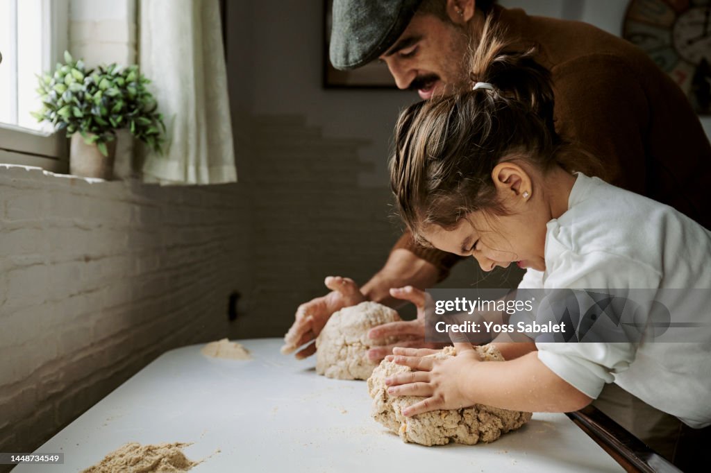Girl with her father making strength while kneading bread