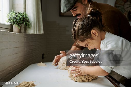 Girl with her father making strength while kneading bread Girl with her father making strength while kneading bread