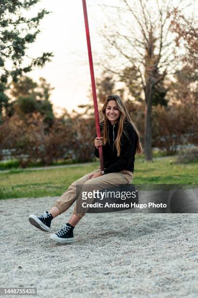 happy teenage blonde girl swinging on a park swing. - using a swing stock pictures, royalty-free photos & images