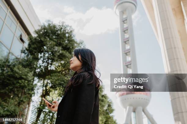 confident asian businesswoman standing in front of landmark buildings in shanghai, china - center for asian american media stock pictures, royalty-free photos & images