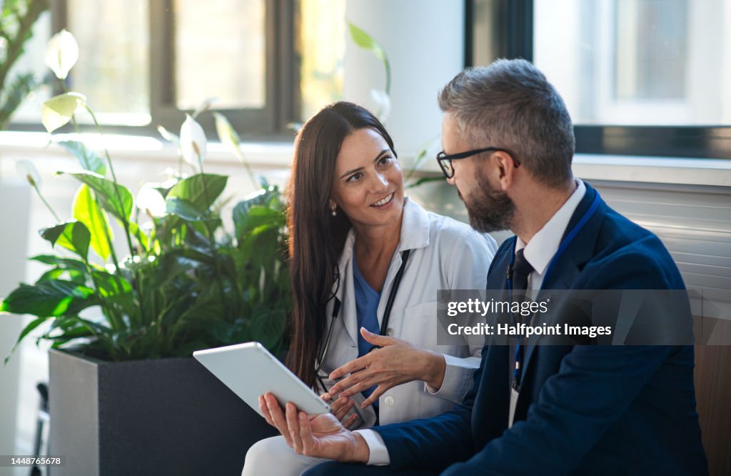 Businessman showing something in digital tablet to doctor