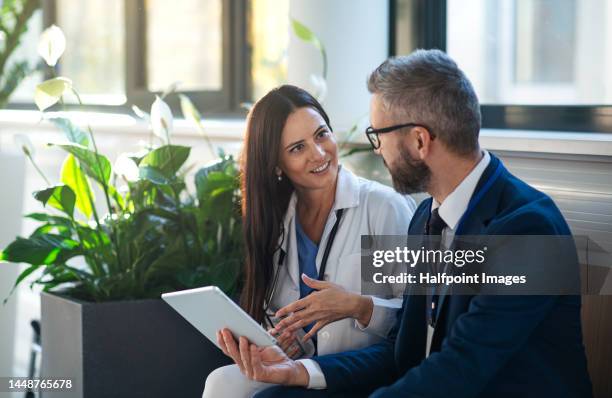 businessman showing something in digital tablet to doctor - medical expertise stock pictures, royalty-free photos & images