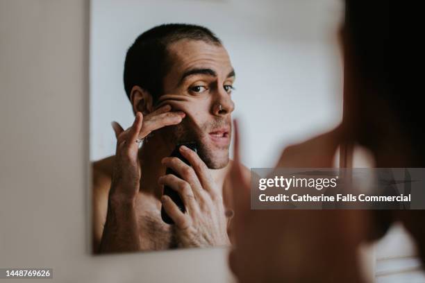 a man shaves his face with an electric shaver - rasieren stock-fotos und bilder