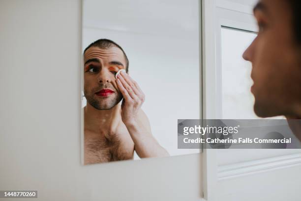 a man removes his eye-make-up with a cotton pad - man eye cream imagens e fotografias de stock