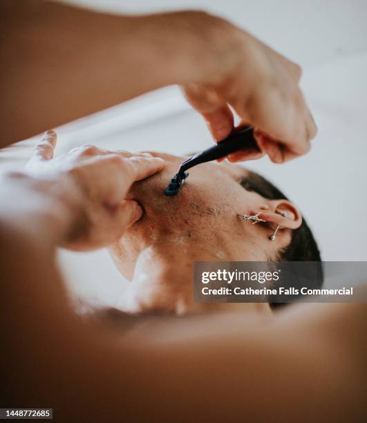 low angel view of a man using a manual razor - foam material stock pictures, royalty-free photos & images