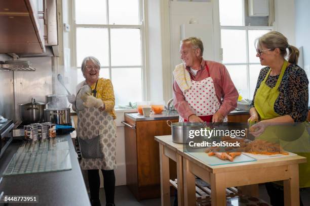 freiwillige kochen in der küche - alter mann kocht stock-fotos und bilder