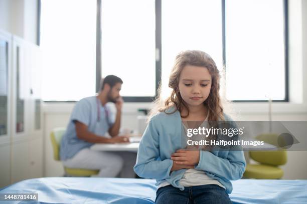 litle girl with pain in belly sitting in doctors office. - doctor abdomen stock pictures, royalty-free photos & images