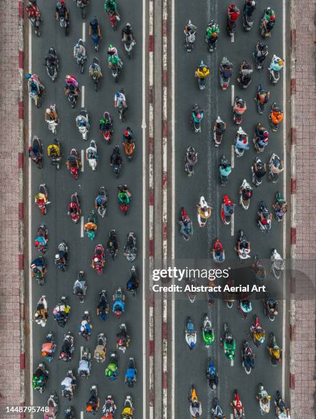 aerial shot directly above a large group of motorcycles crossing a road bridge, ho chi minh city, vietnam - zuid vietnam stockfoto's en -beelden