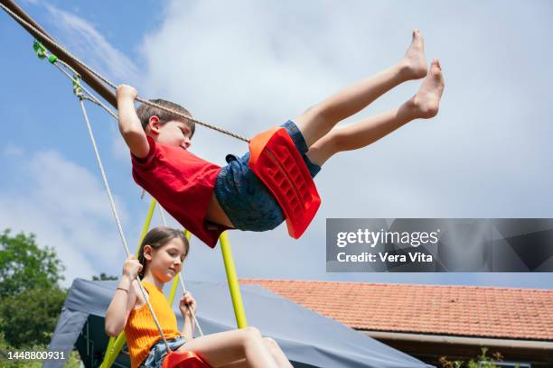 little girl and boy having fun on house swing barefoot at summer holidays. - family sports centre laughing stock-fotos und bilder