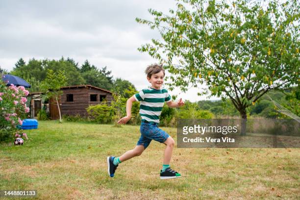 little boy in green casual clothes running on the garden in holidays. - corrida de ponto imagens e fotografias de stock