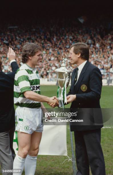 Celtic captain Roy Aitken lifts the Scottish Premier Division Championship Trophy with manager Billy McNeill before the home match against...