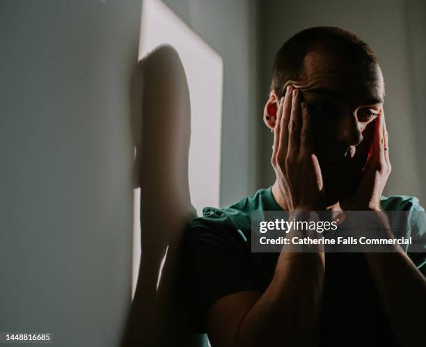 a man rubs his temples as though experiencing pain or despair - zelfmoord stockfoto's en -beelden