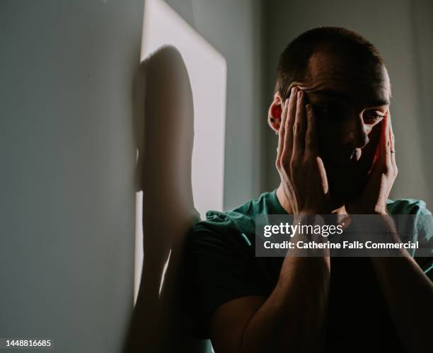 a man rubs his temples as though experiencing pain or despair - suicide imagens e fotografias de stock