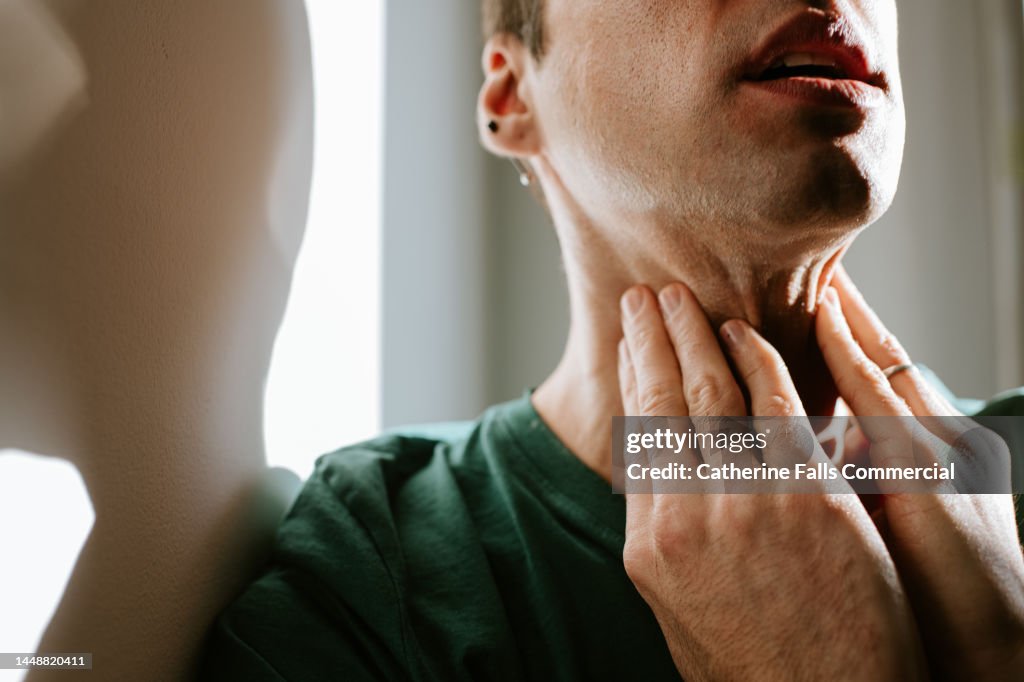 A man massages a sore neck / throat