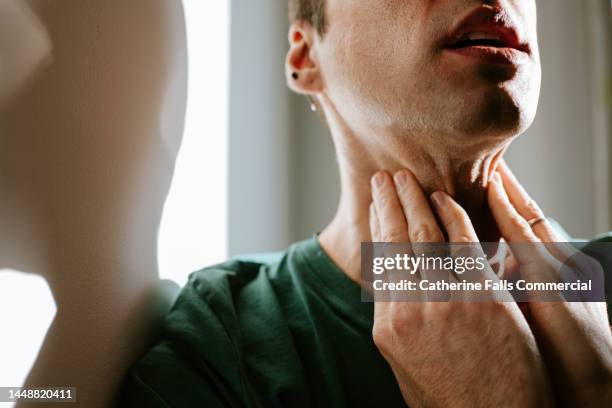 a man massages a sore neck / throat - human mouth stock photos et images de collection