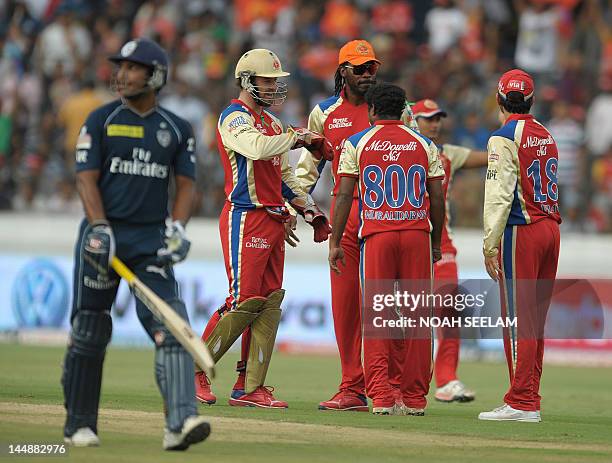 Royal Challengers Bangalore bowler Muttiah Muralitharan celebrates with teammates Chris Gayle and AB De Villers after taking the wicket of unseen...