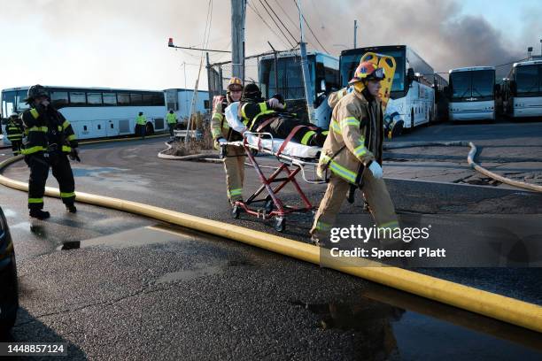 An injured firefighter is taken away on a stretcher as firefighters and other emergency personnel work to control a large fire in the Brooklyn...