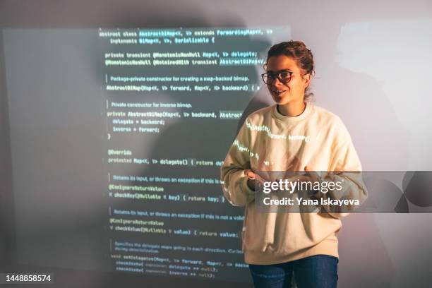 woman programmer teaches students how to code with a console projection on the wall - it skills stock-fotos und bilder