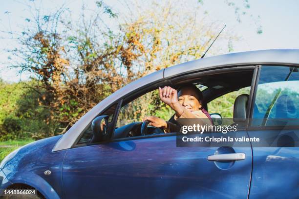 young woman leaning out of car window, saying hi - zwaaien gebaren stockfoto's en -beelden