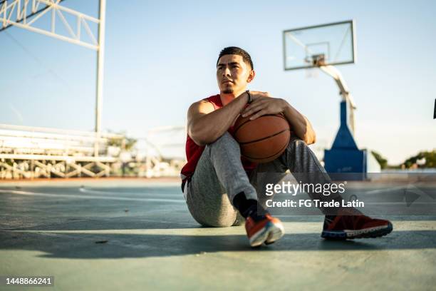 basketball player sitting on the sports court - basketball hoop stockfoto's en -beelden