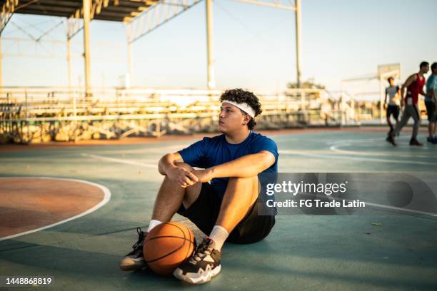 basketball player sitting on the sports court - unfair competition stock pictures, royalty-free photos & images