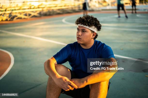 basketball player sitting on the sports court - toxisch sociaal concept stockfoto's en -beelden