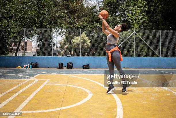 young woman shooting the ball to the basket - african american basketball stock pictures, royalty-free photos & images
