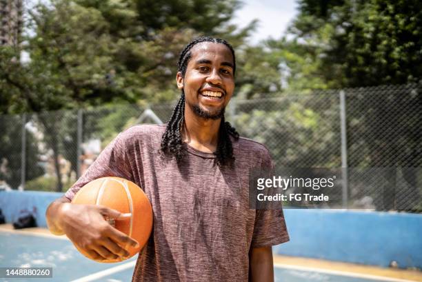 portrait of a young man holding a basketball ball in a sports court - man goatee stock pictures, royalty-free photos & images