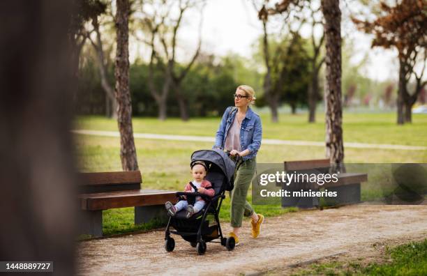 mother and daughter: a walk in the park - pram stock pictures, royalty-free photos & images