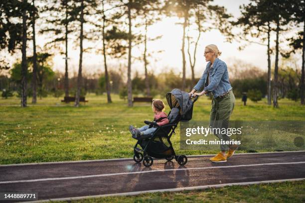 mother and daughter: a walk in the park - kinderwagen stockfoto's en -beelden