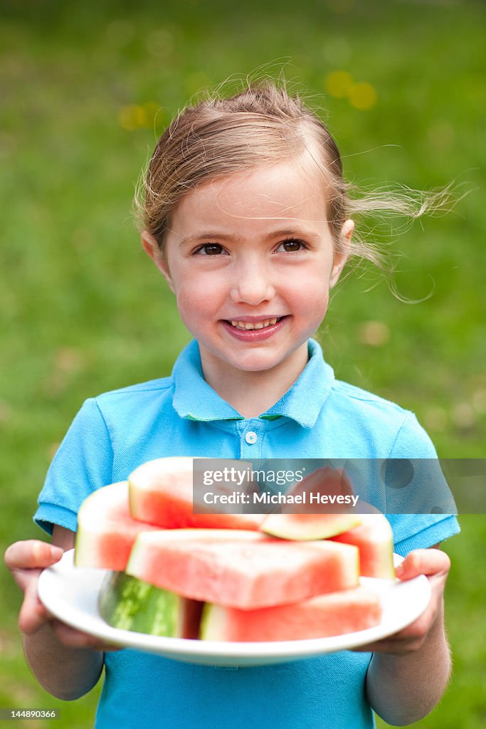 A young girl holding a plate of watermelon