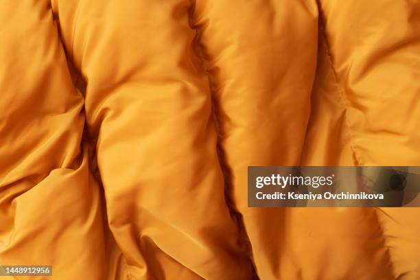 down jacket fabric background, orange puffer jacket texture - puffer jacket stock pictures, royalty-free photos & images