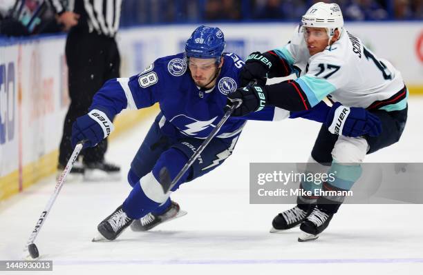 Mikhail Sergachev of the Tampa Bay Lightning and Jaden Schwartz of the Seattle Kraken fight for the puck during a game at Amalie Arena on December...