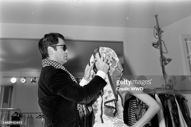 Designer Karl Lagerfeld adjusts a model's scarf.