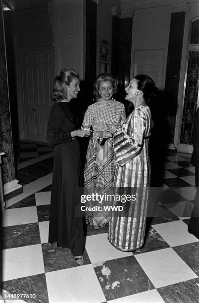 Louise Shepard and Cynthia Colt confer with a guest at a dinner dance hosted by Lynn Wyatt.