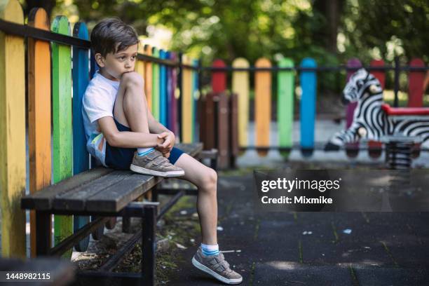 niño triste sentado en un banco - banco de jogadores fotografías e imágenes de stock