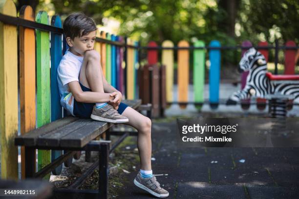 sad boy sitting on a bench - solitude stockfoto's en -beelden