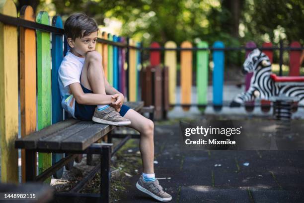 sad boy sitting on a bench - abandoned playground stock pictures, royalty-free photos & images