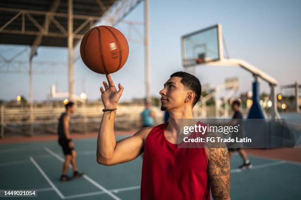 joven haciendo girar una pelota de baloncesto en un campo - spinning fotografías e imágenes de stock