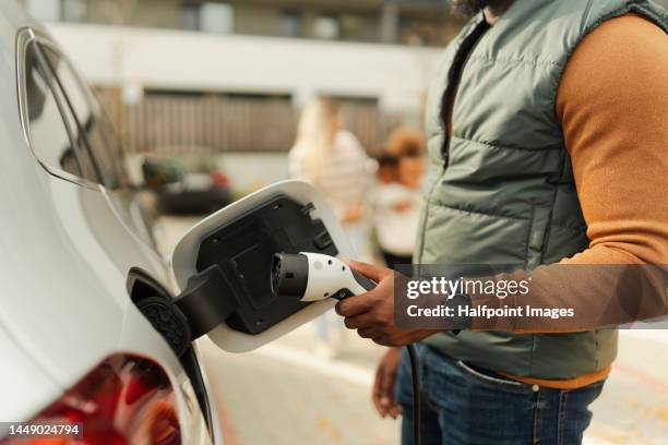 close-up of young multiracial man charging electric car. - slovakia people stock pictures, royalty-free photos & images